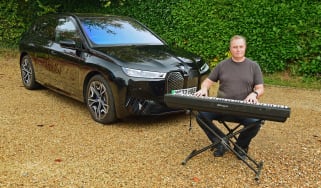 Auto Express editor-in-chief Steve Fowler playing a keyboard while sitting next to our long-term BMW iX