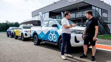 Hydrogen fuel-cell powered Toyota Hilux with Auto Express consumer reporter Tom Jervis talking to a Toyota engineer in front of some pick-up trucks