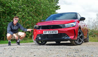 Auto Express senior news reporter Alastair Crooks crouching next to the Vauxhall Corsa GS wearing a pair of vizor sunglasses