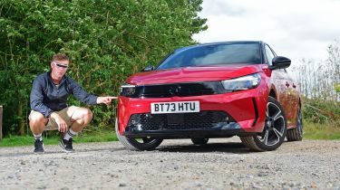 Auto Express senior news reporter Alastair Crooks crouching next to the Vauxhall Corsa GS wearing a pair of vizor sunglasses