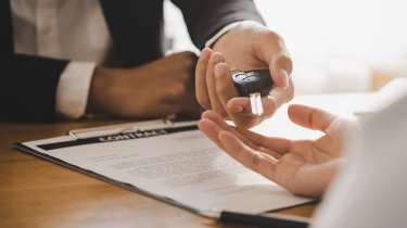 Salesperson handing car key to customer