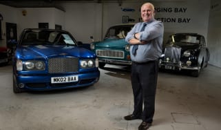 Jim Ronan standing with three classic cars