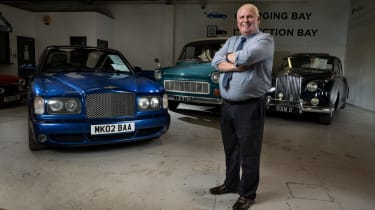 Jim Ronan standing with three classic cars