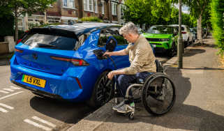 Wheelchair user plugging a charging cable into a Vauxhall Astra Electric