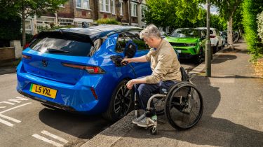 Wheelchair user plugging a charging cable into a Vauxhall Astra Electric