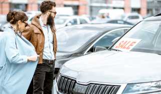 Two people browsing a car dealership forecourt
