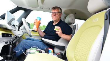 Auto Express editor Paul Barker sitting in the Volkswagen ID.Buzz while holding a Pringles can