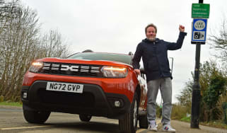 Auto Express web producer Pete Baiden standing next to the Dacia Duster and a ULEZ road sign