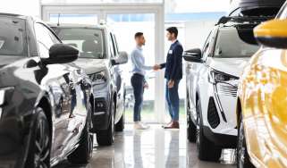 Car salesperson shaking hands with a customer in a showroom