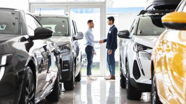 Car salesperson shaking hands with a customer in a showroom