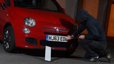 Thief stealing a Fiat 500&#039;s number plate