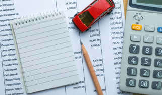 Calculator, model car, pencil and notebook on desk