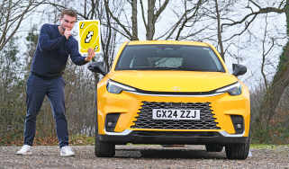 Auto Express senior news reporter Alastair Crooks standing next to the Lexus LBX while holding a giant Uno playing card