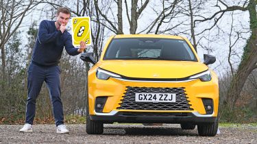 Auto Express senior news reporter Alastair Crooks standing next to the Lexus LBX while holding a giant Uno playing card