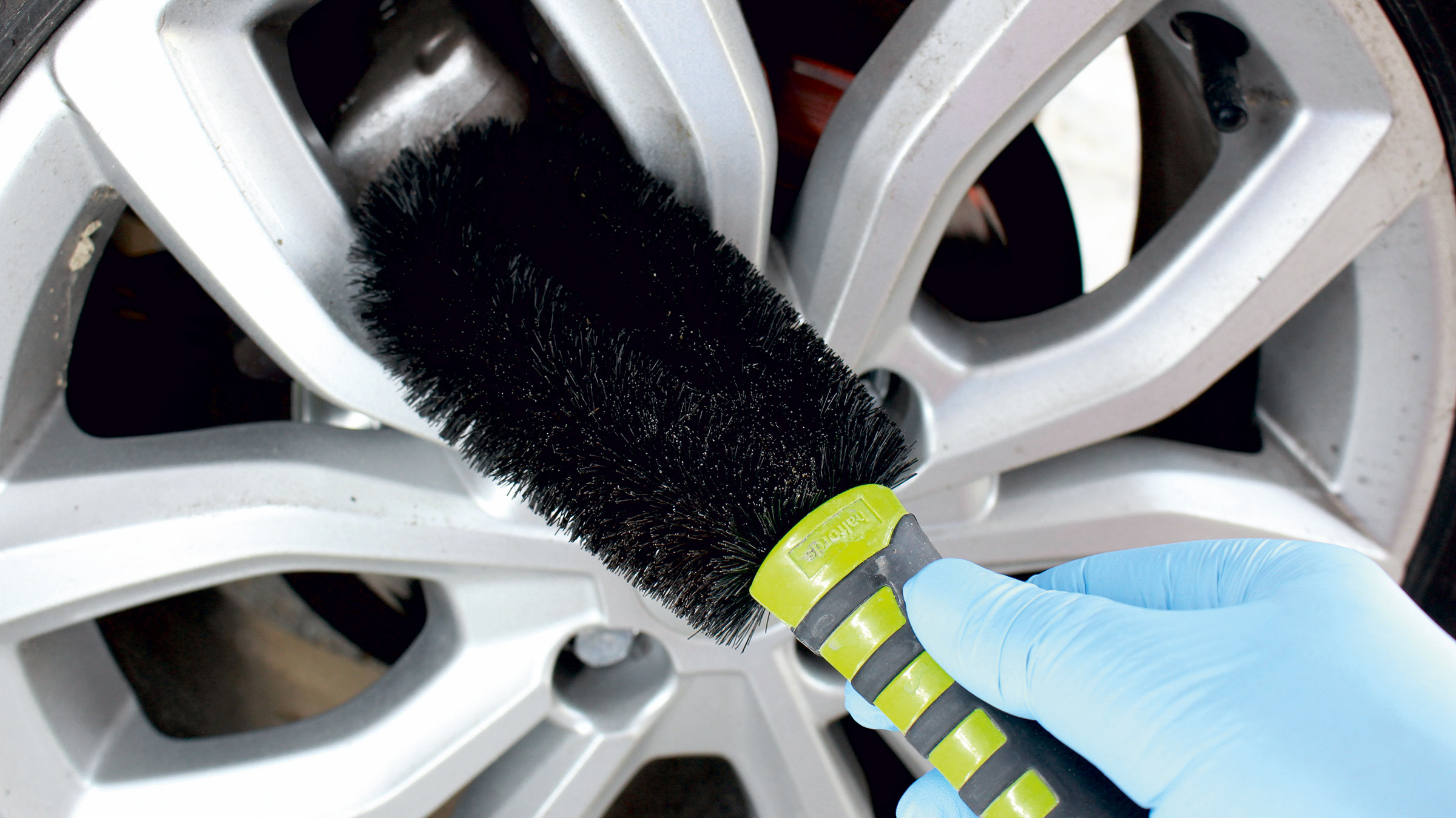 Woman cleaning car wheel with detailing brush