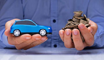 Hands holding a toy car and coins