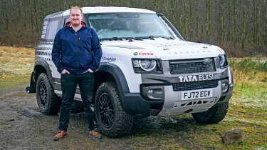 Auto Express news reporter Ellis Hyde standing next to a land Rover Defender