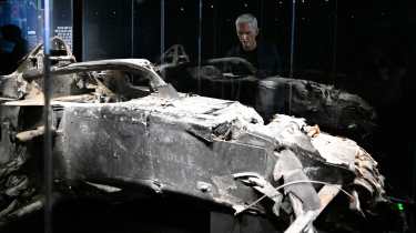 Damon Hill looking at a burned F1 car on display at London F1 exhibition