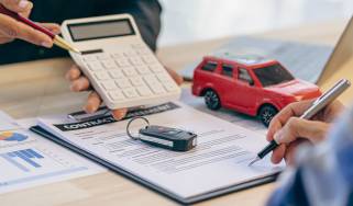 Finance contract, car key and calculator on desk