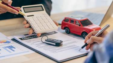 Finance contract, car key and calculator on desk