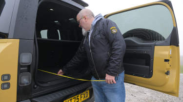 Auto Express senior test editor Dean Gibson inspecting the Land Rover Defender 110 Trophy Edition's boot