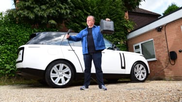 Auto Express editor-in-chief Steve Fowler holding a charging cable and gerry can while standing in front of the Range Rover
