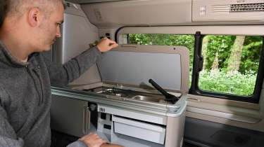 Auto Express deputy editor Richard Ingram sitting operating the Volkswagen California eHybrid's on-board kitchenette