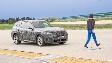 BMW X3 prototype (camouflaged) driving towards a pedestrian crash test dummy