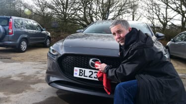 Auto Express senior photographer Pete Gibson cleaning the Mazda 3&#039;s badge