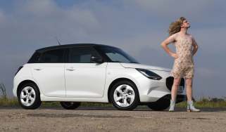 Auto Express consumer reporter Tom Jervis dressed as Taylor Swift while standing next to the Suzuki Swift