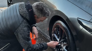 Auto Express senior photographer Pete Gibson cleaning the Mazda 3&#039;s wheels
