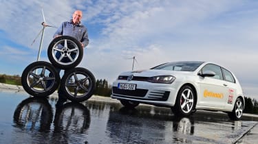 Auto Express products editor Kim Adams standing behind a stack of tyres and next to a Volkswagen Golf Mk7 
