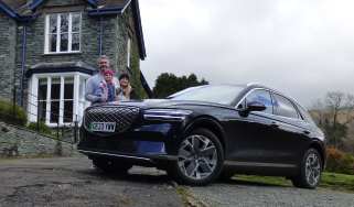 Auto Express deputy editor Richard Ingram and family standing with the Genesis Electrified GV70 outside a country house