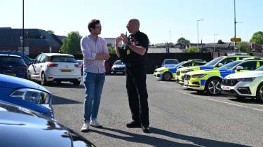 Auto Express consumer reporter Tom Jervis talking to PC Mark Jones in front of a fleet of police cars