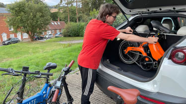 Person loading a folding e-bike into a car boot