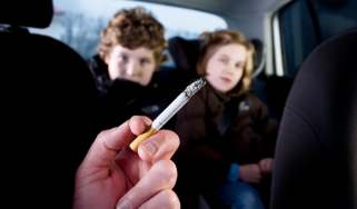 Person smoking in car in front of children