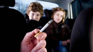 Person smoking in car in front of children