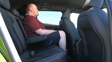 Auto Express news reporter Ellis Hyde sitting in the Peugeot E-408's rear seat