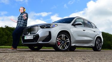 Auto Express news reporter Ellis Hyde leaning against the BMW iX1