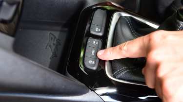 Auto Express senior news reporter Alastair Crooks pointing at the sport button in the Vauxhall Corsa GS