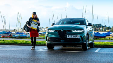 Auto Express pictures editor Dawn Grant standing next to the Alfa Romeo Tonale PHEV while holding a road atlas