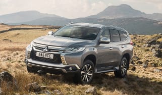 A Shogun Sport on a rough, rocky and grassy terrain with mountains in the background