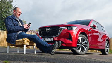 Auto Express chief sub-editor Andy Pringle sitting reading his phone in front of Mazda CX-60