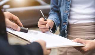 Person signing a document attached to a clipboard