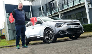 Auto Express executive editor Paul Adam standing next to the Citroen C4 X and wearing foam hands