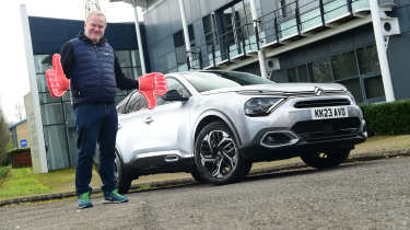 Auto Express executive editor Paul Adam standing next to the Citroen C4 X and wearing foam hands