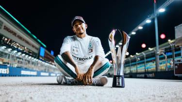 Lewis Hamilton sitting next to a trophy
