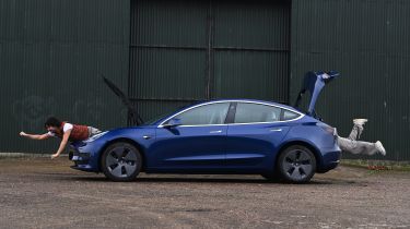 Auto Express senior staff writer Jordan Katsianis leaning out of the Tesla&#039;s front and rear storage areas