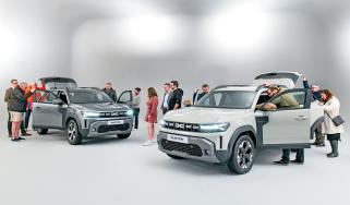 Group of Dacia Duster owners standing in a room with two brand-new Dacia Dusters