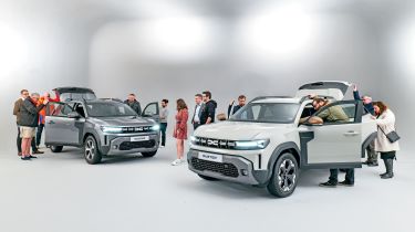 Group of Dacia Duster owners standing in a room with two brand-new Dacia Dusters